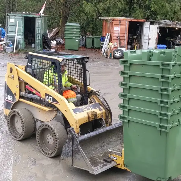 Skid steer moving commercial garbage bins in the yard